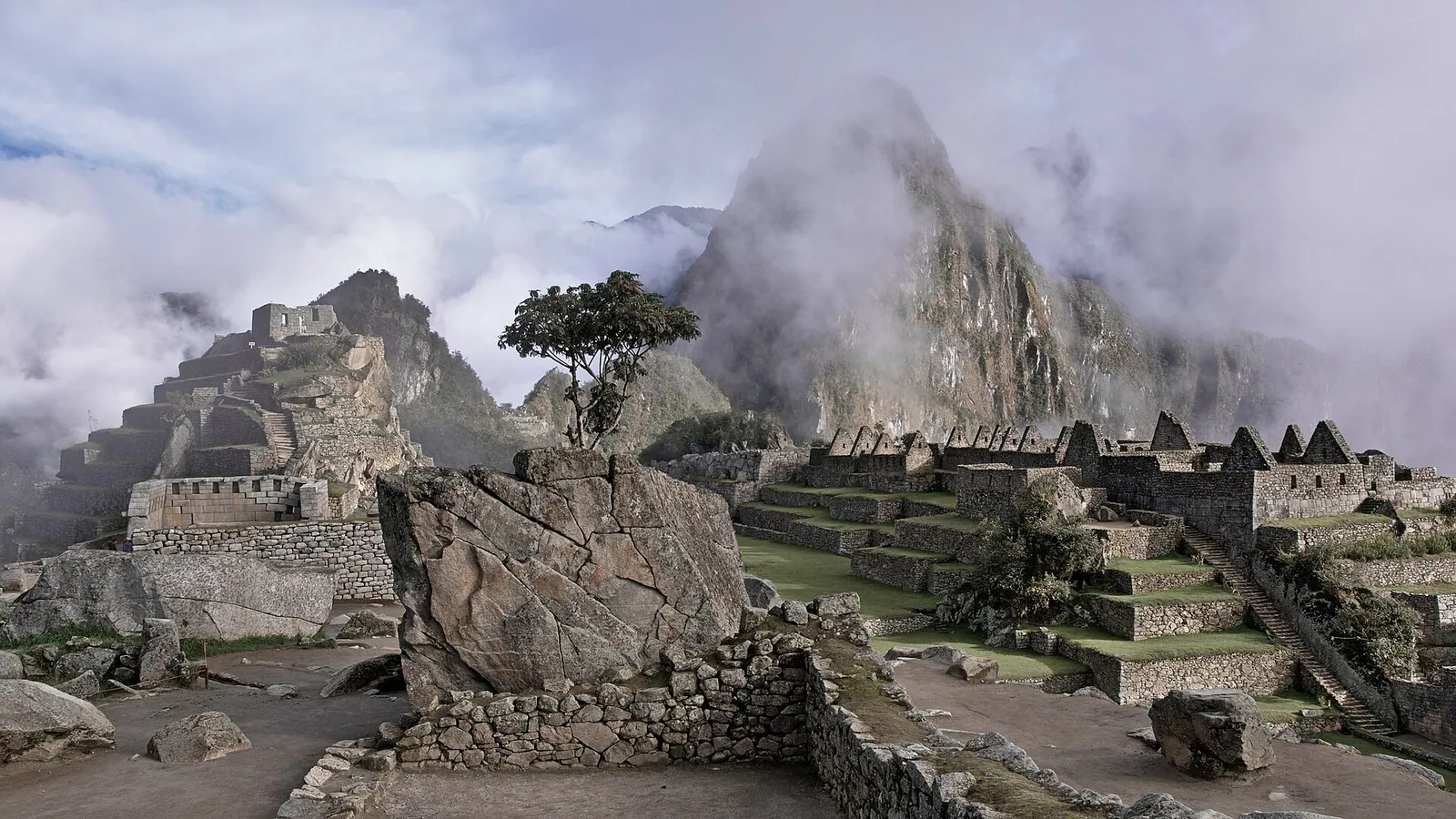 The stone terraces and ruins of Machu Picchu among misty green mountains in Peru
