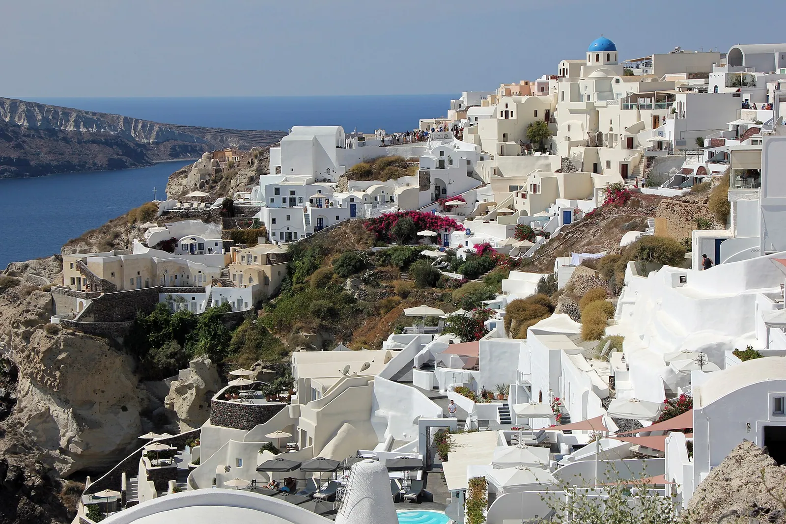 White-washed houses stepping down a cliffside in Oia, on Santorini, above the deep blue Aegean Sea