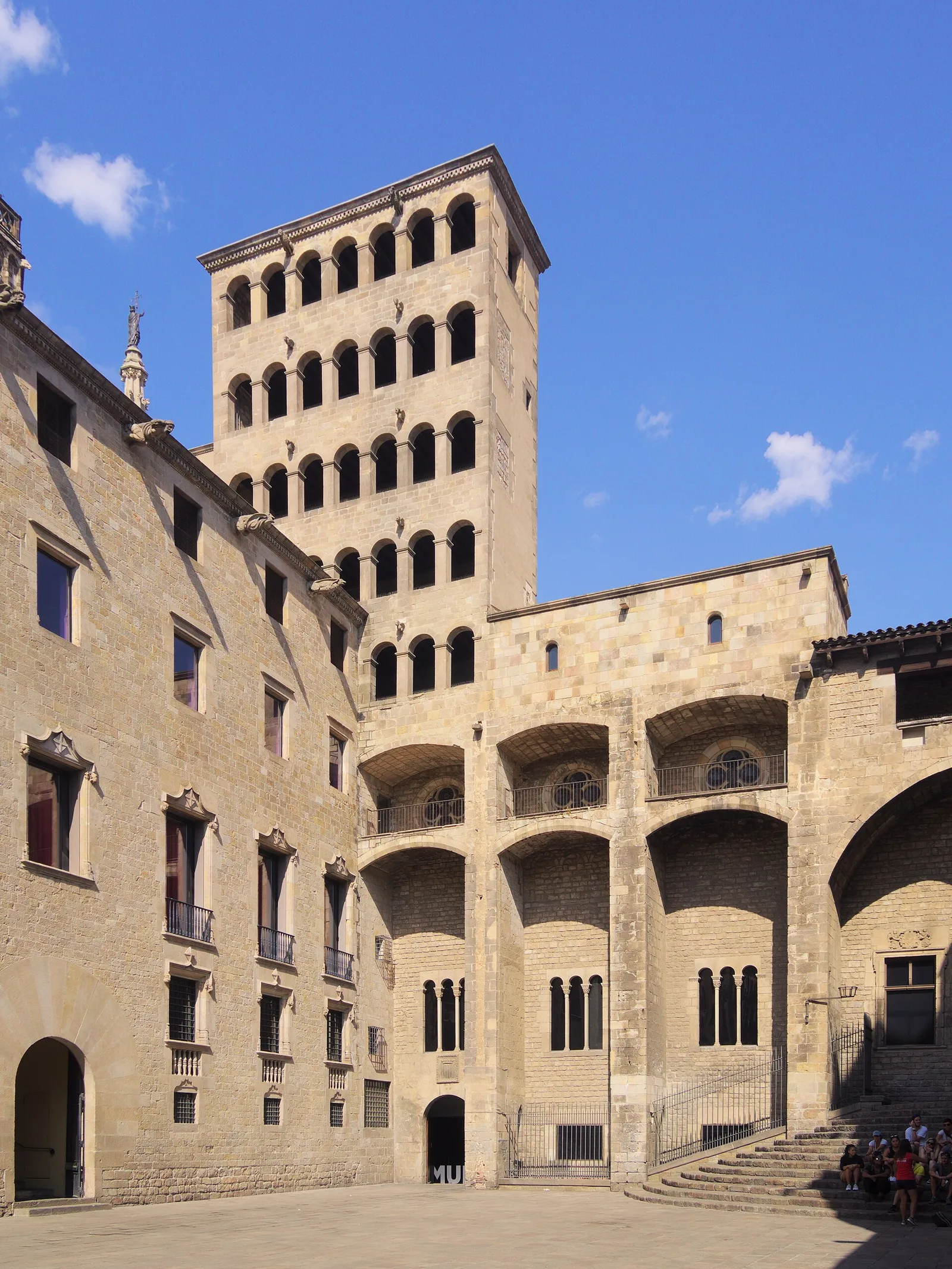 A medieval stone tower with arched openings rising above old stone buildings in the Gothic Quarter