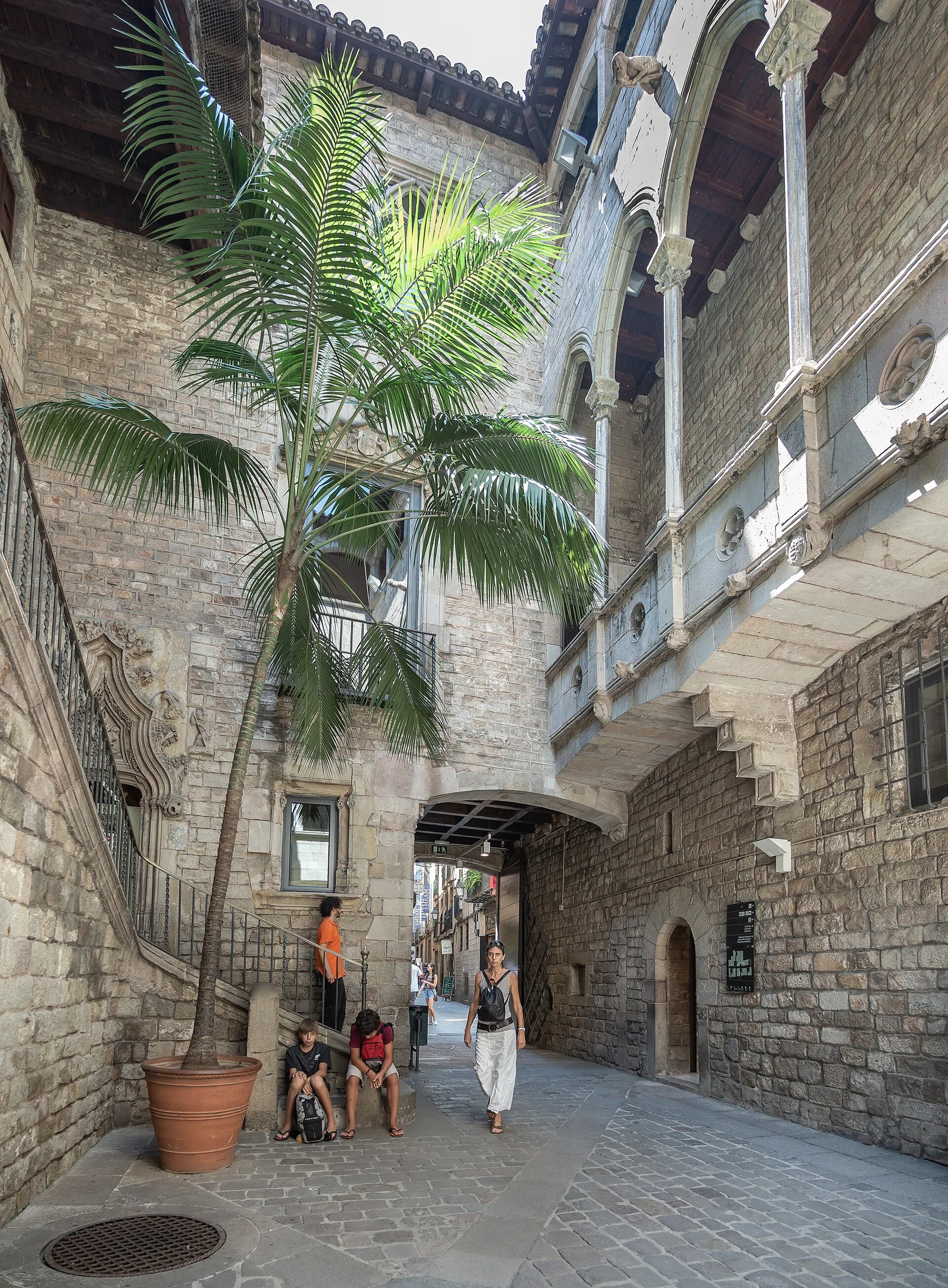 A stone courtyard with a palm tree and a carved gallery balcony in a medieval palace