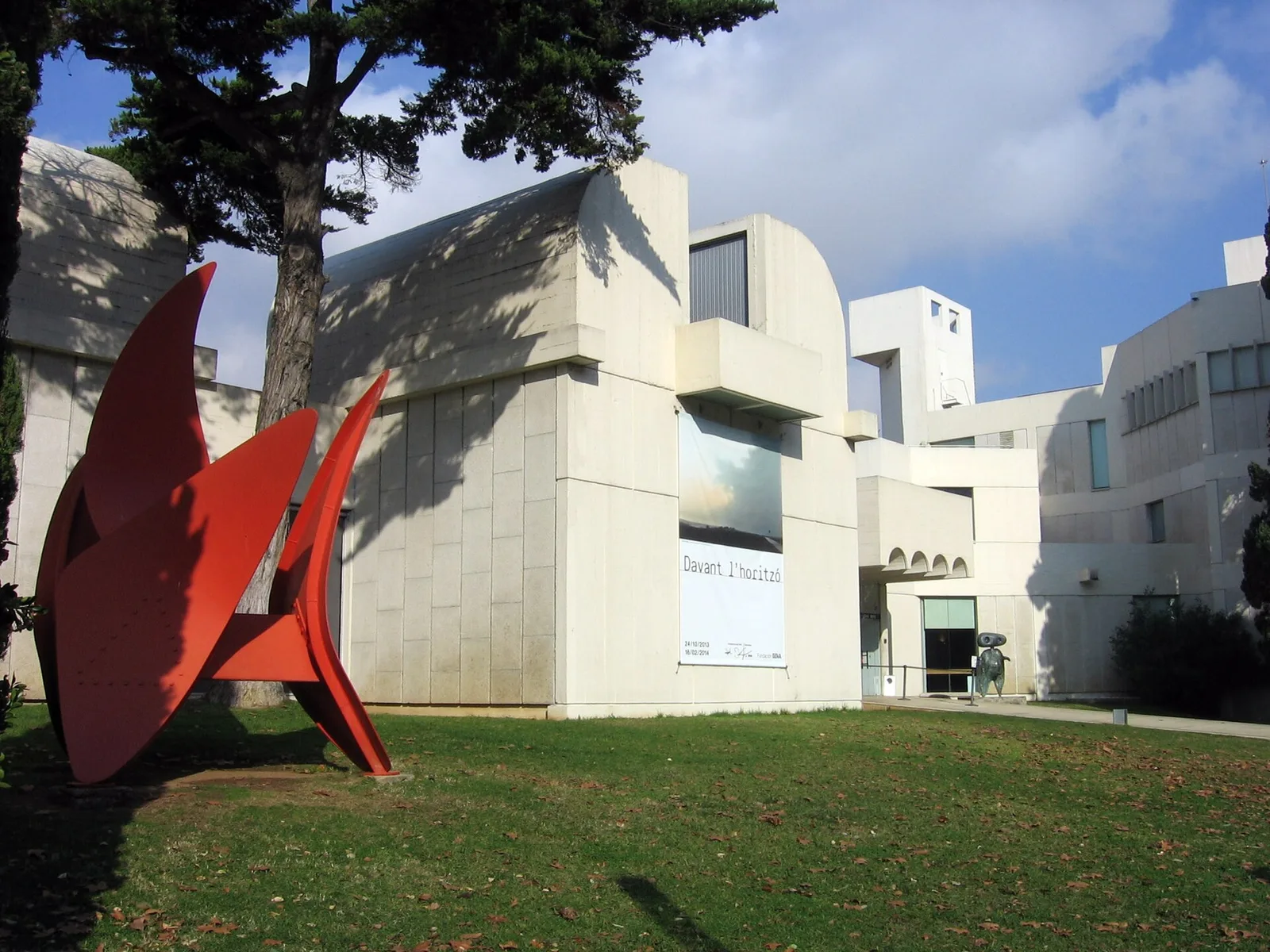 A red abstract sculpture in front of the white, angular building of the Fundació Joan Miró