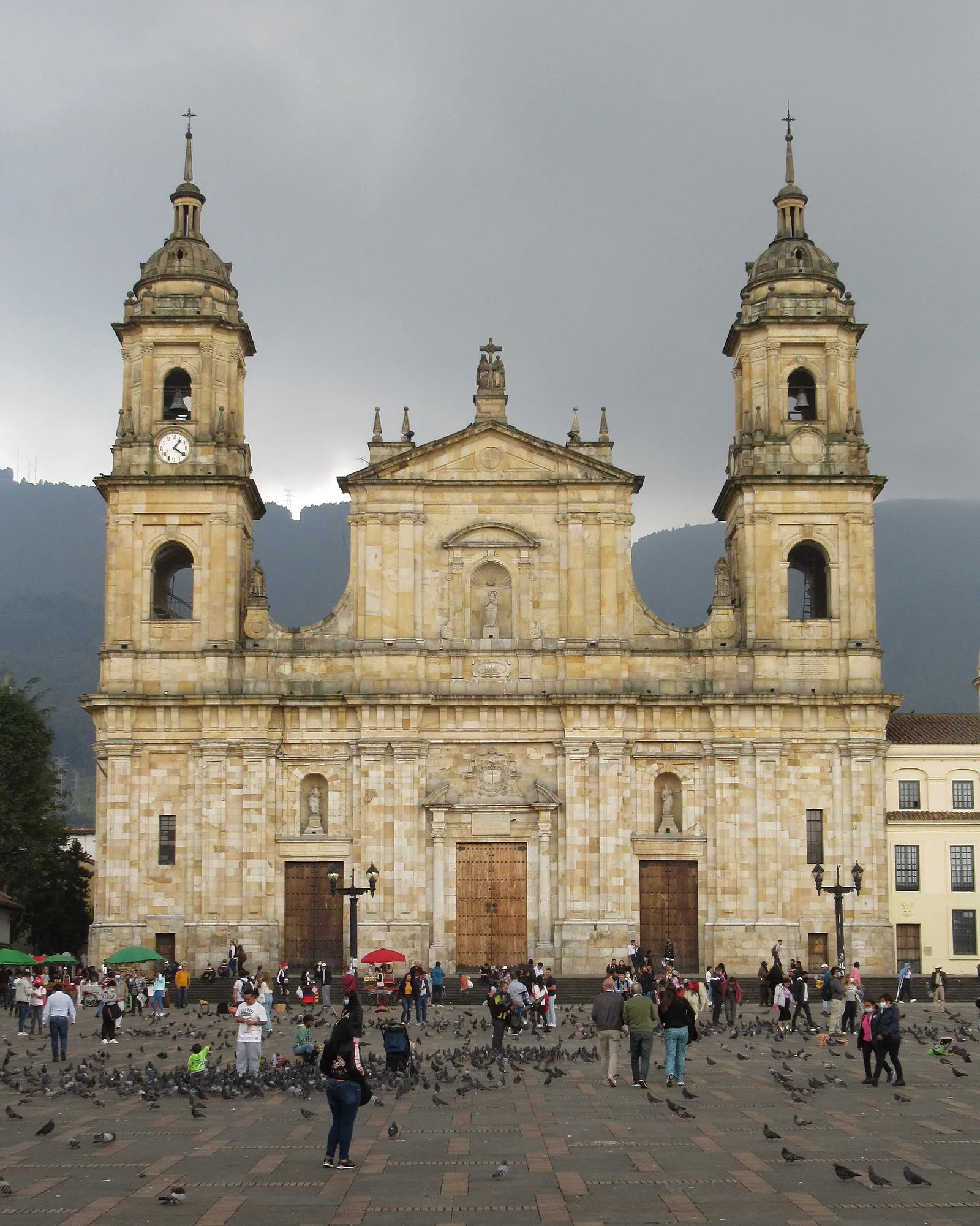 The twin-towered, cream-colored facade of the Primate Cathedral of Colombia under a gray sky