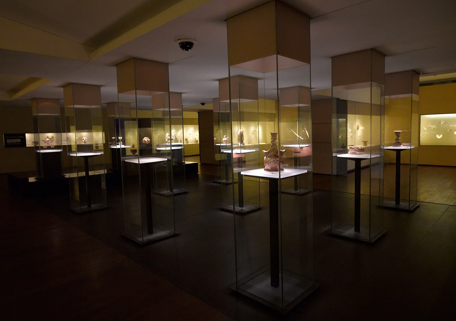 Rows of glass display cases with lit gold artifacts in a darkened gallery of the Gold Museum