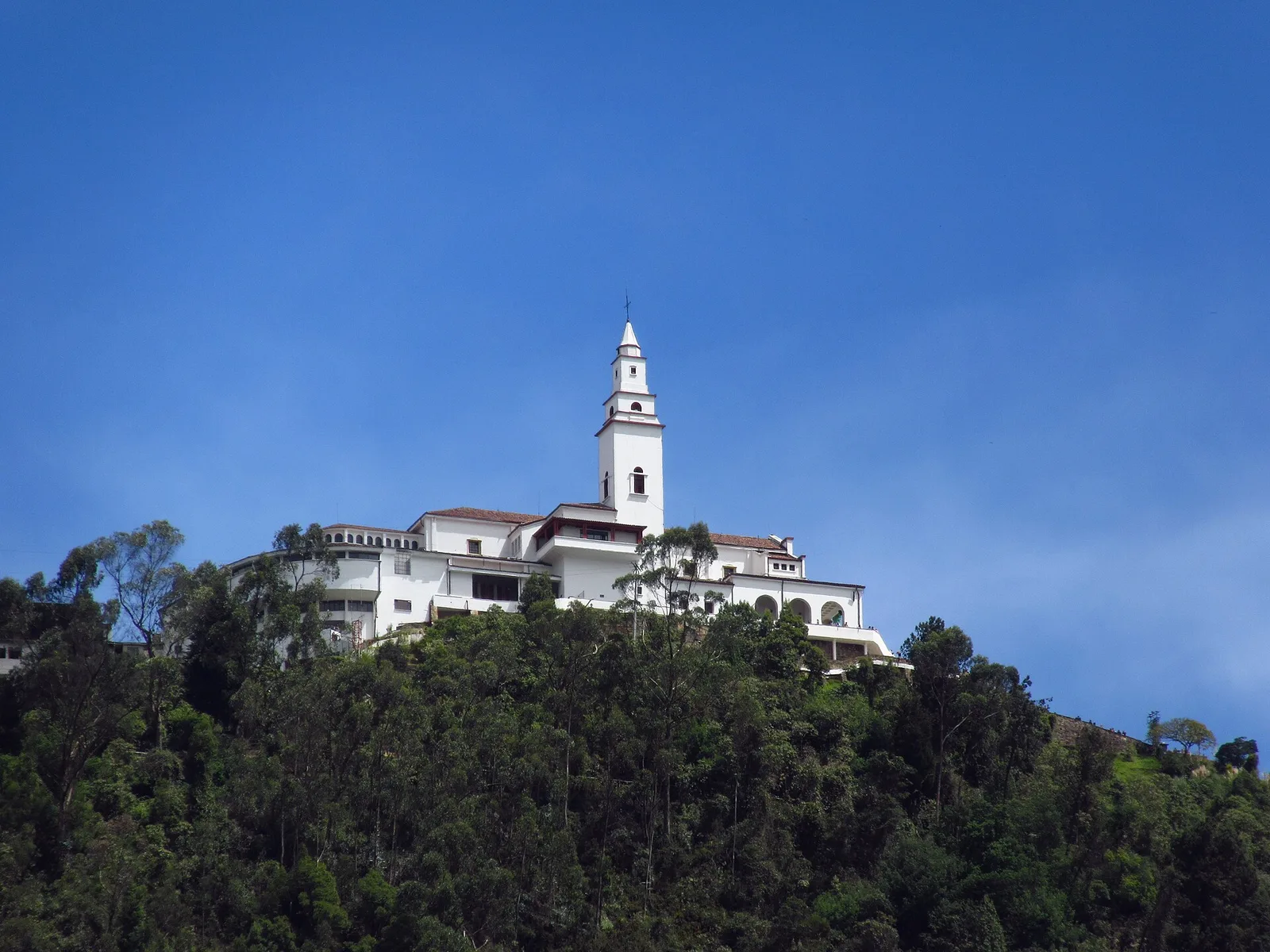 The white church of Monserrate on its forested hilltop under a blue sky