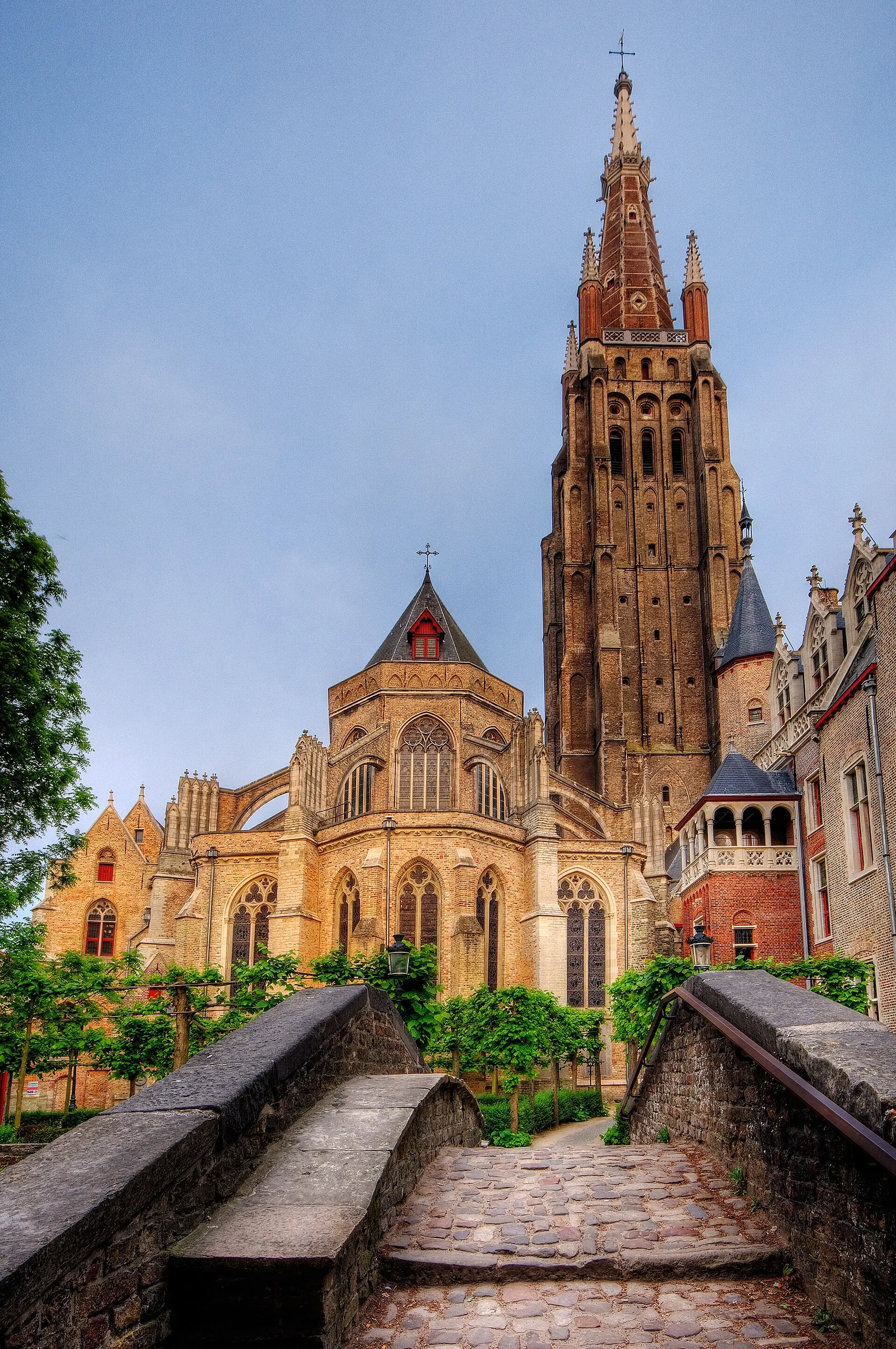 The brick tower and apse of the Church of Our Lady seen from a cobbled canal bridge