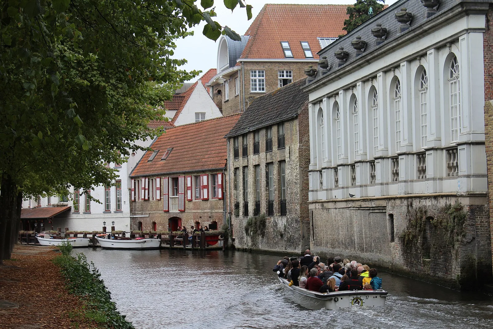 A canal boat passing old brick houses along the Dijver in Bruges
