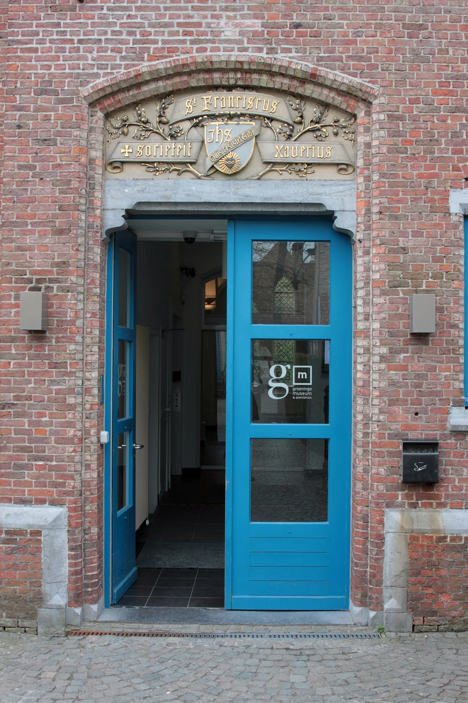 The blue entrance door of the Groeninge Museum in a red-brick wall