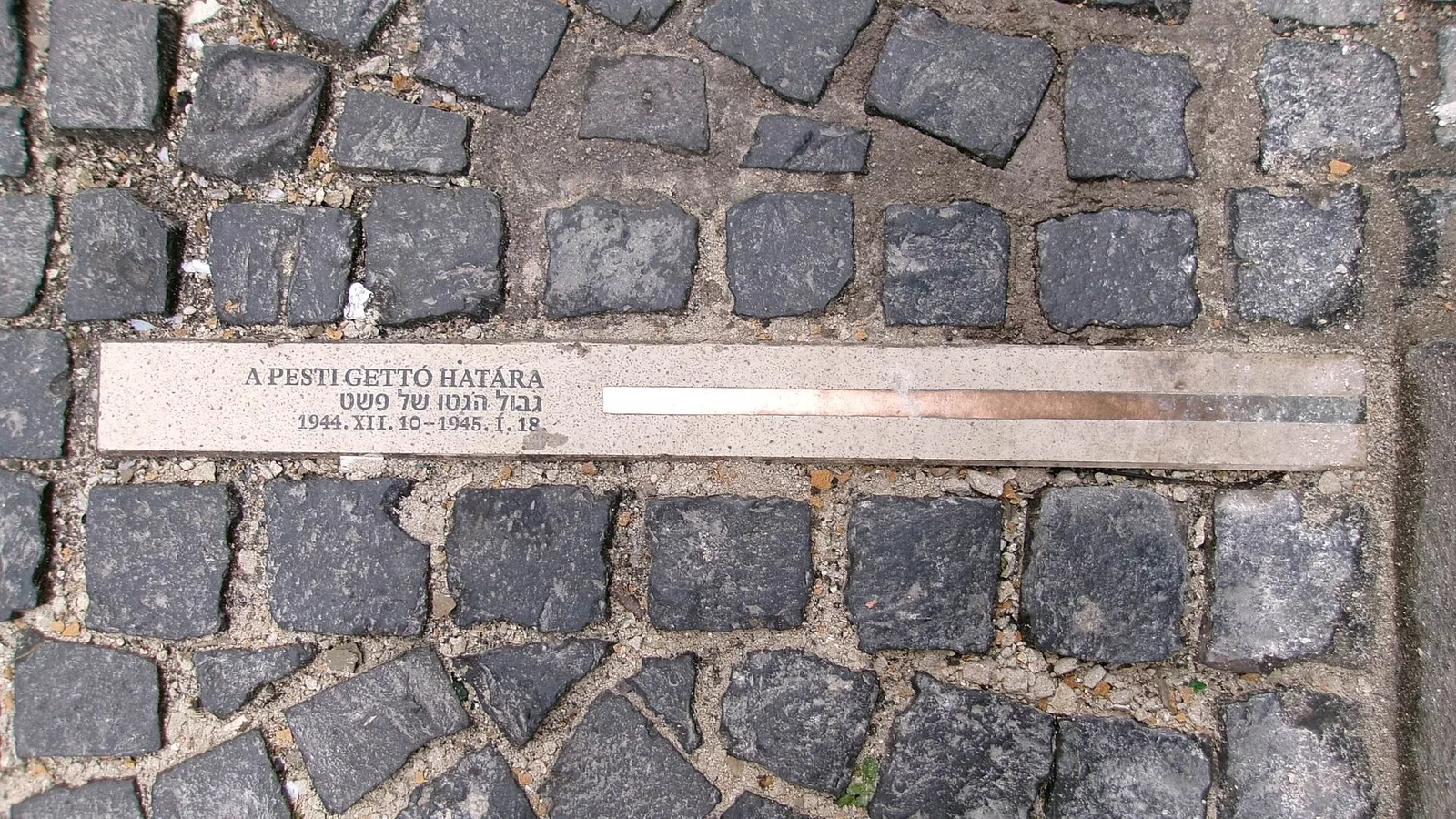 A metal strip set in the cobblestones, inscribed with the words “A Pesti Gettó határa”, marking the boundary of the Pest ghetto