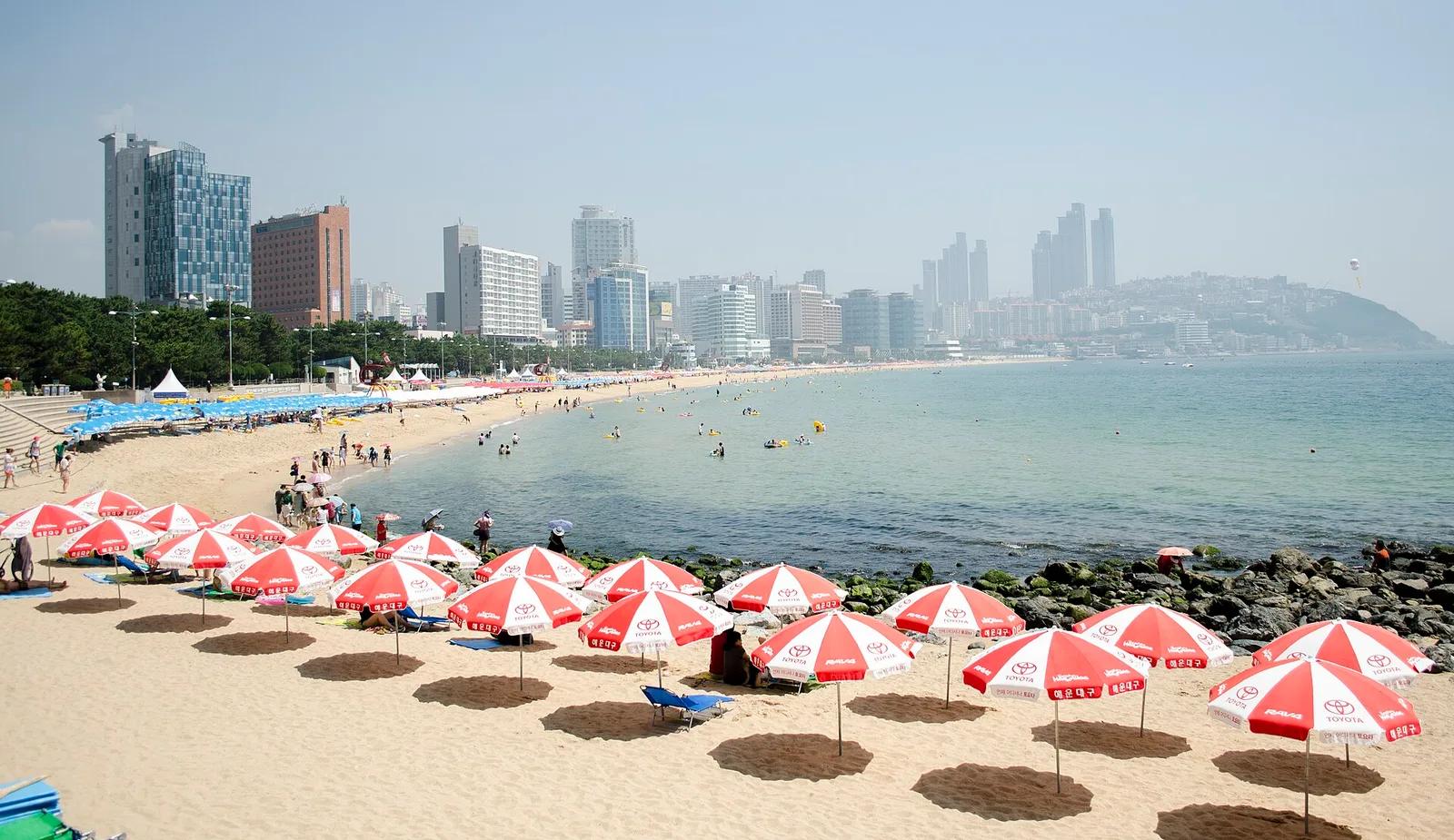 Haeundae Beach packed with red-and-white parasols, with the high-rise skyline behind
