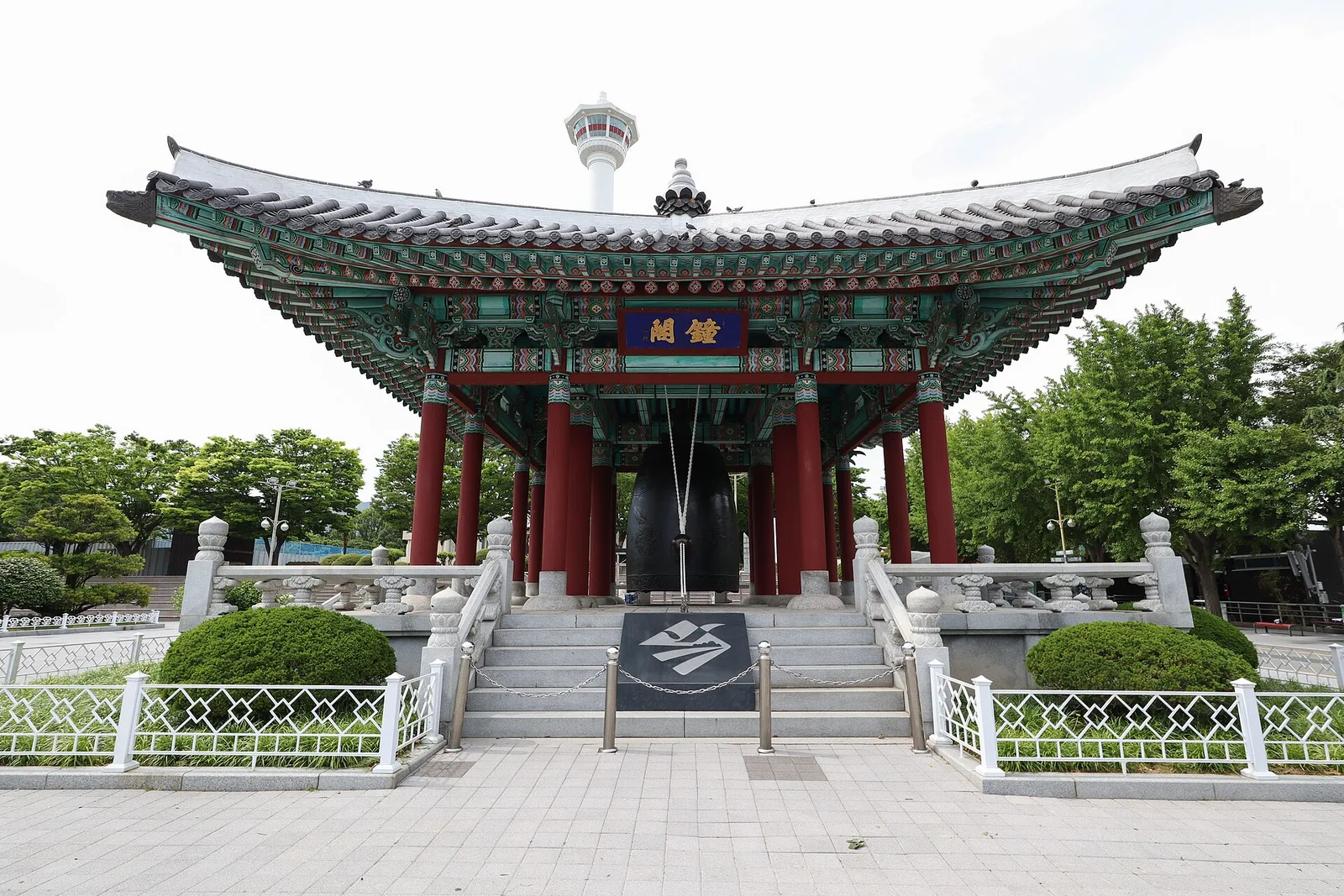 A traditional pavilion in Yongdusan Park with the Busan Tower rising behind it