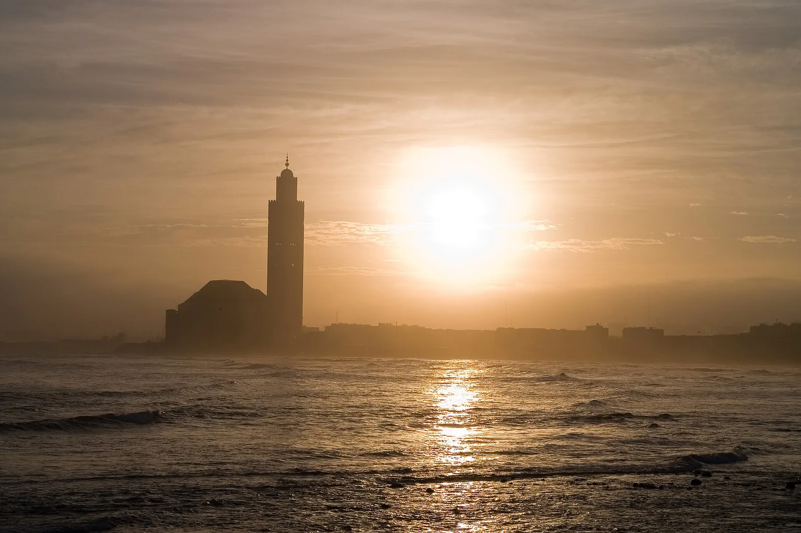 The minaret of the Hassan II Mosque silhouetted against a setting sun over the Atlantic