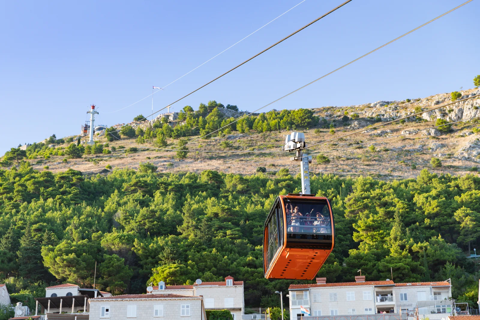 A cable car cabin climbing the pine-covered slope of Mount Srđ above Dubrovnik