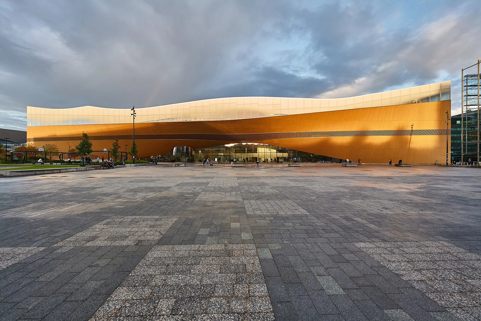 The long, curving timber-clad facade of Helsinki Central Library Oodi glowing in evening light