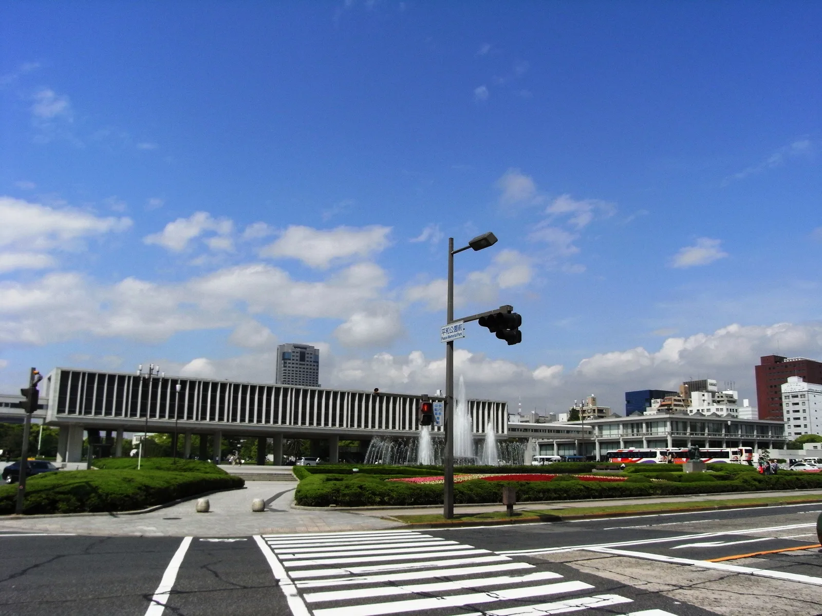 The long, elevated concrete building of the Hiroshima Peace Memorial Museum seen across a street under a blue sky