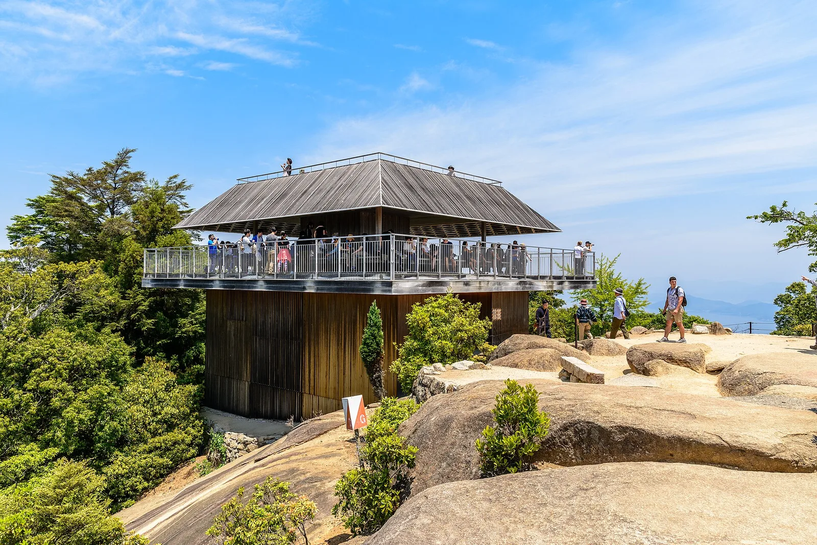 The wooden observatory building on the rocky summit area of Mount Misen under a blue sky