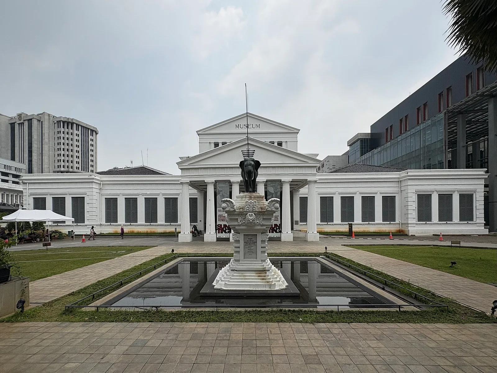 The neoclassical front of the National Museum of Indonesia, with a pool and an elephant statue in the foreground