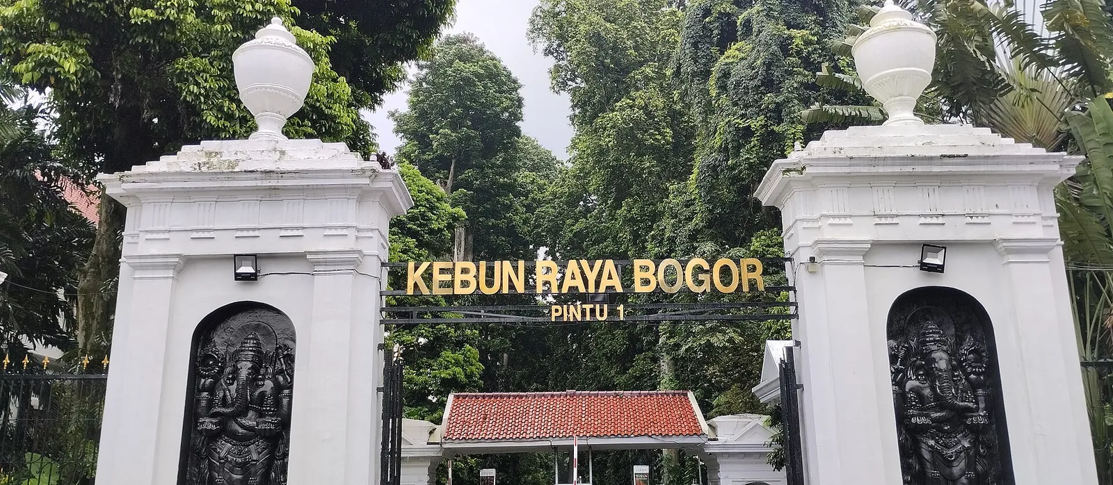 The Kebun Raya Bogor main entrance gate, with white pillars and Ganesha reliefs