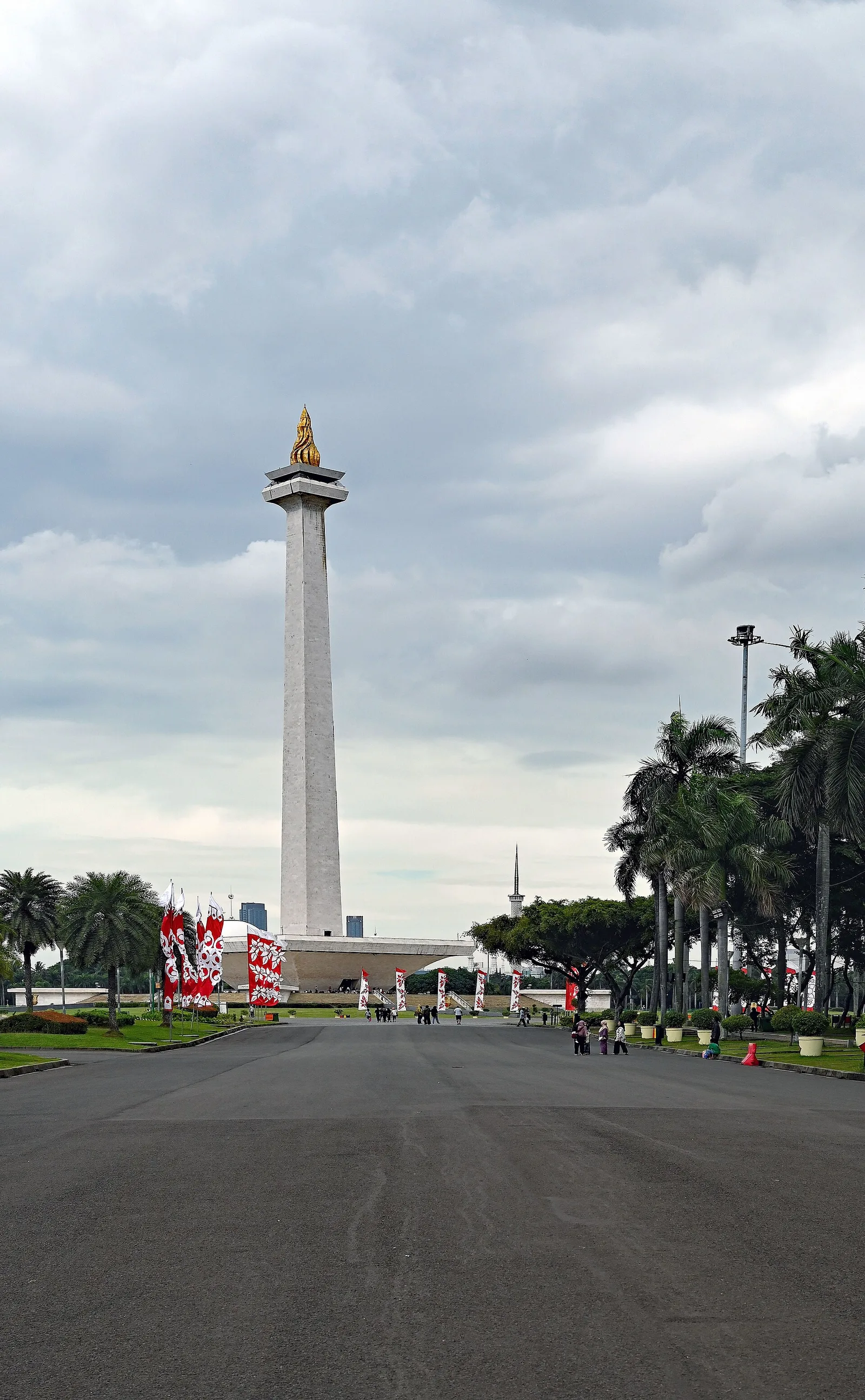 The white National Monument tower with its gold flame, seen across the wide plaza of Monas park