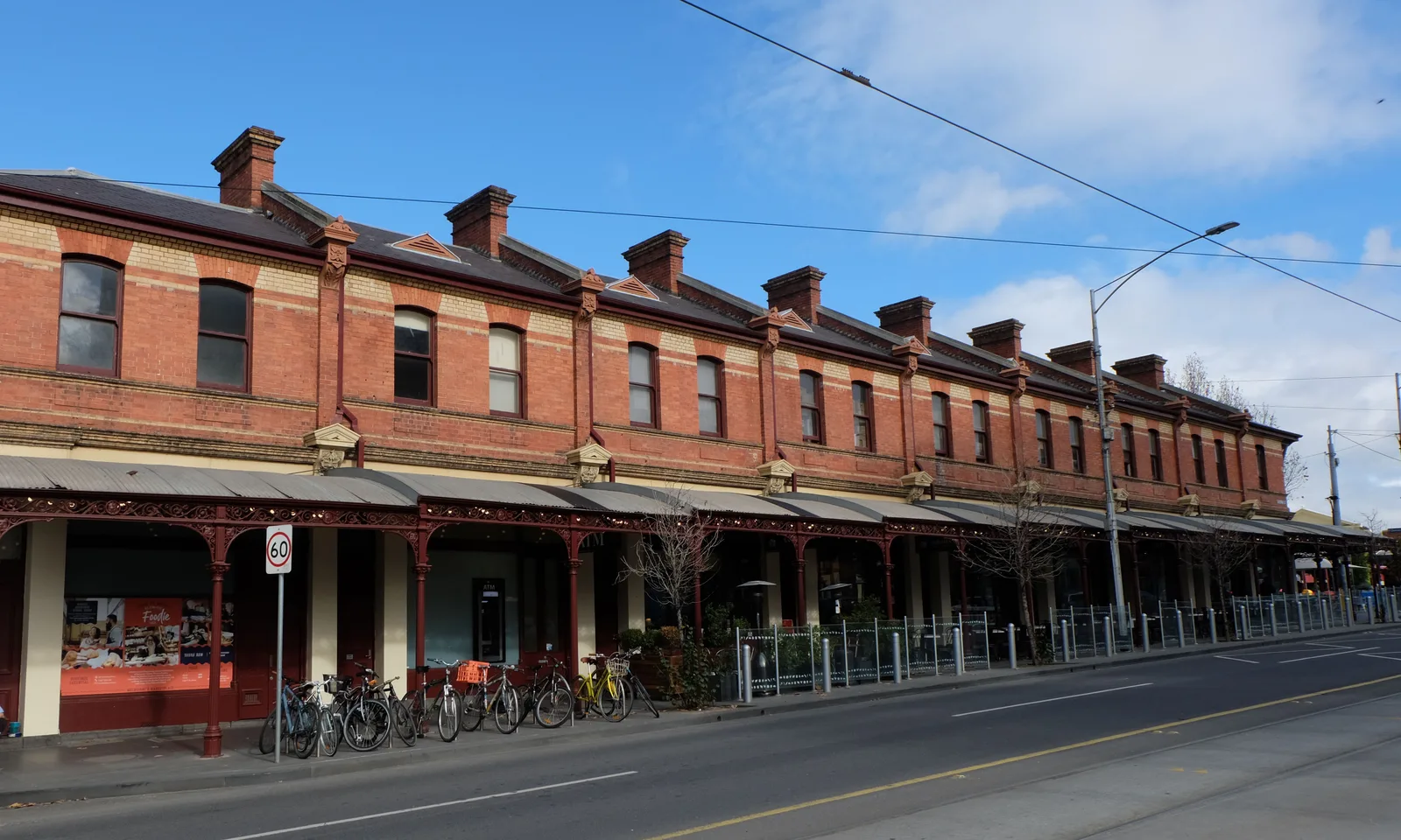Red-brick terrace shopfronts with iron-lace verandahs along Victoria Street beside Queen Victoria Market