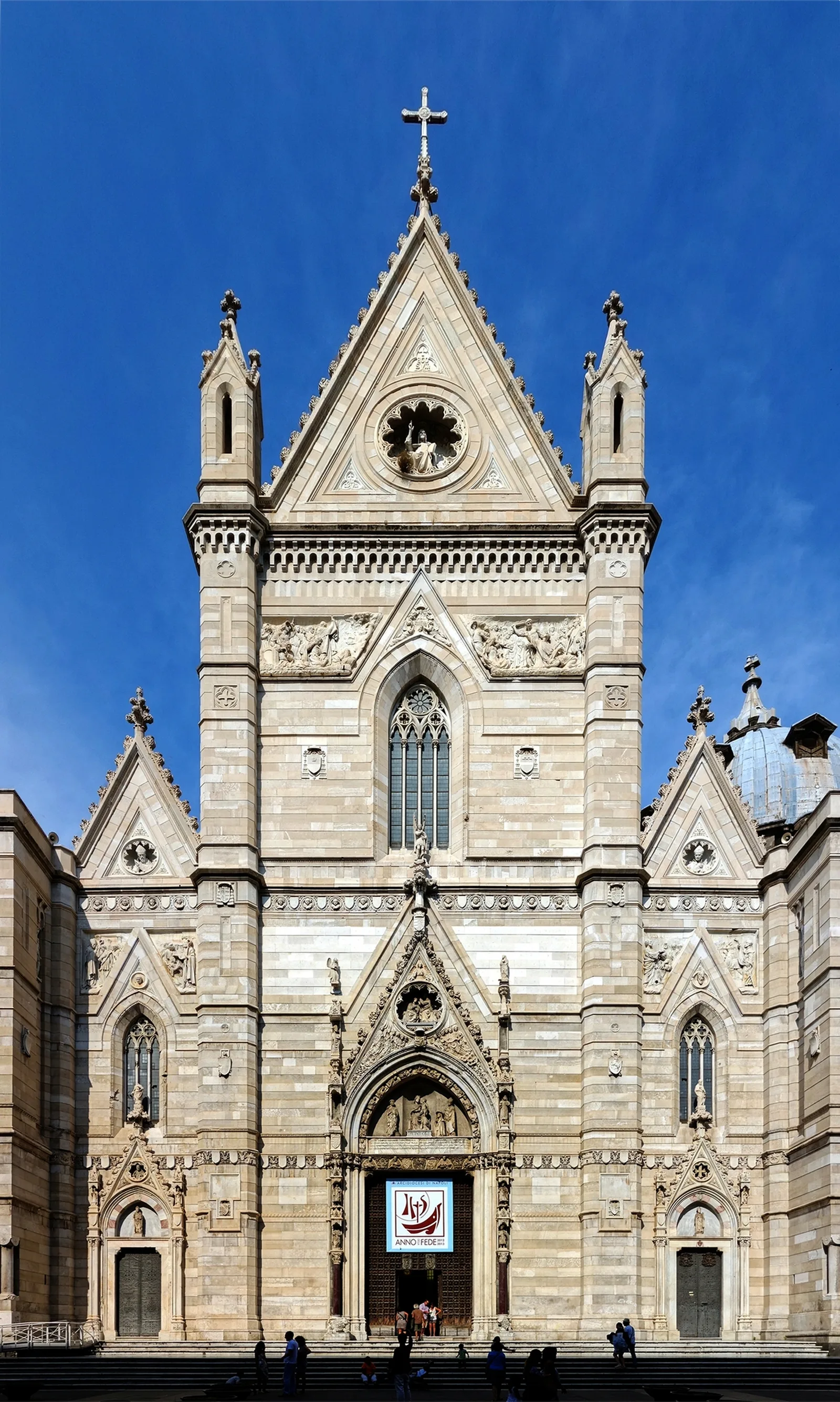 The pointed neo-Gothic facade of the Naples Cathedral against a blue sky