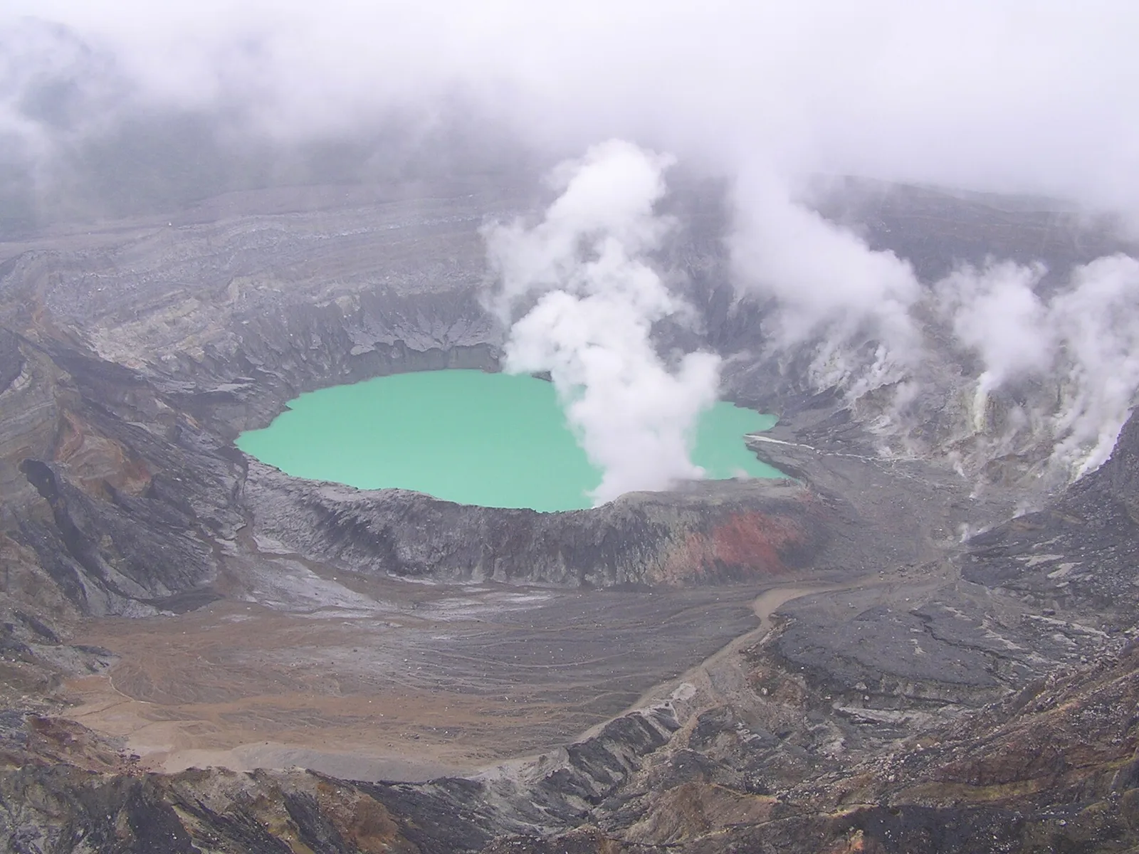 The Poás crater with a turquoise acid lake and steam rising from the rocky floor