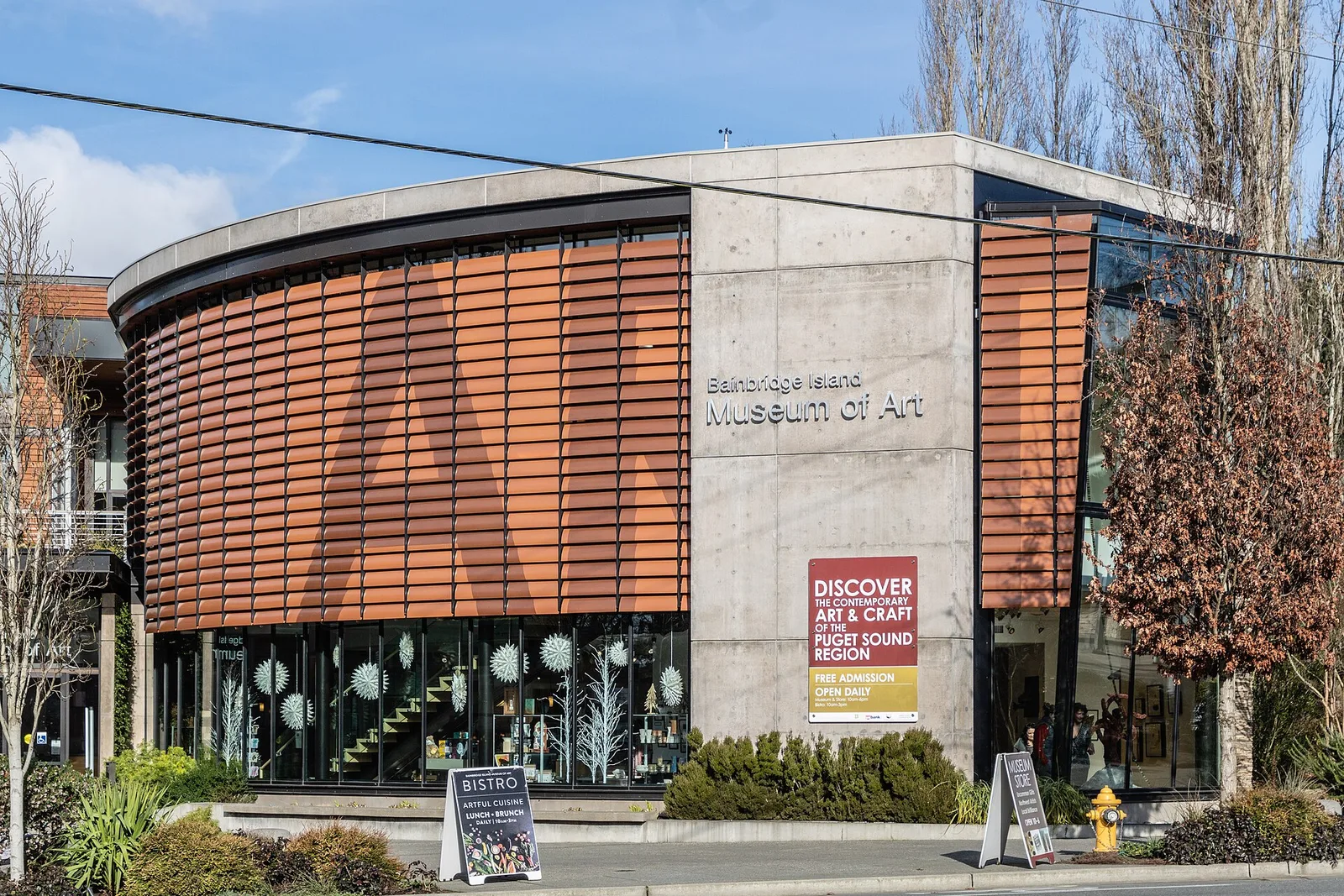 The curved, wood-slatted facade of the Bainbridge Island Museum of Art on a street corner in Winslow