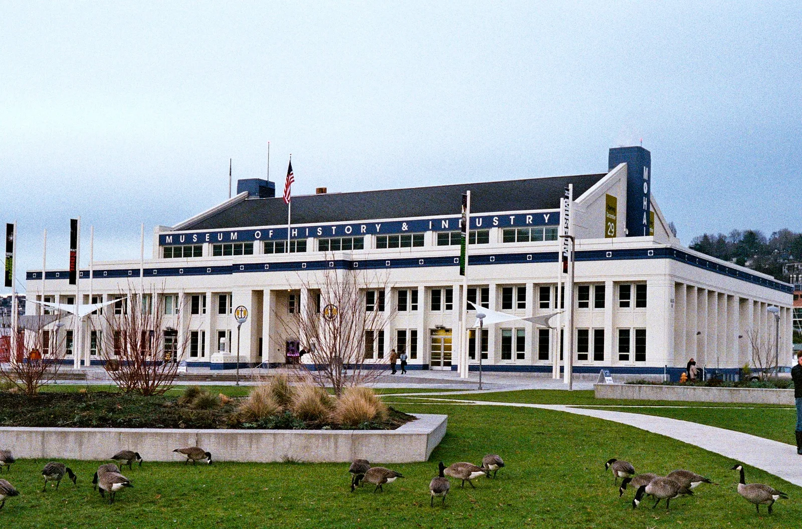 The white, flag-topped Armory building that houses the Museum of History & Industry, with geese on the lawn in front