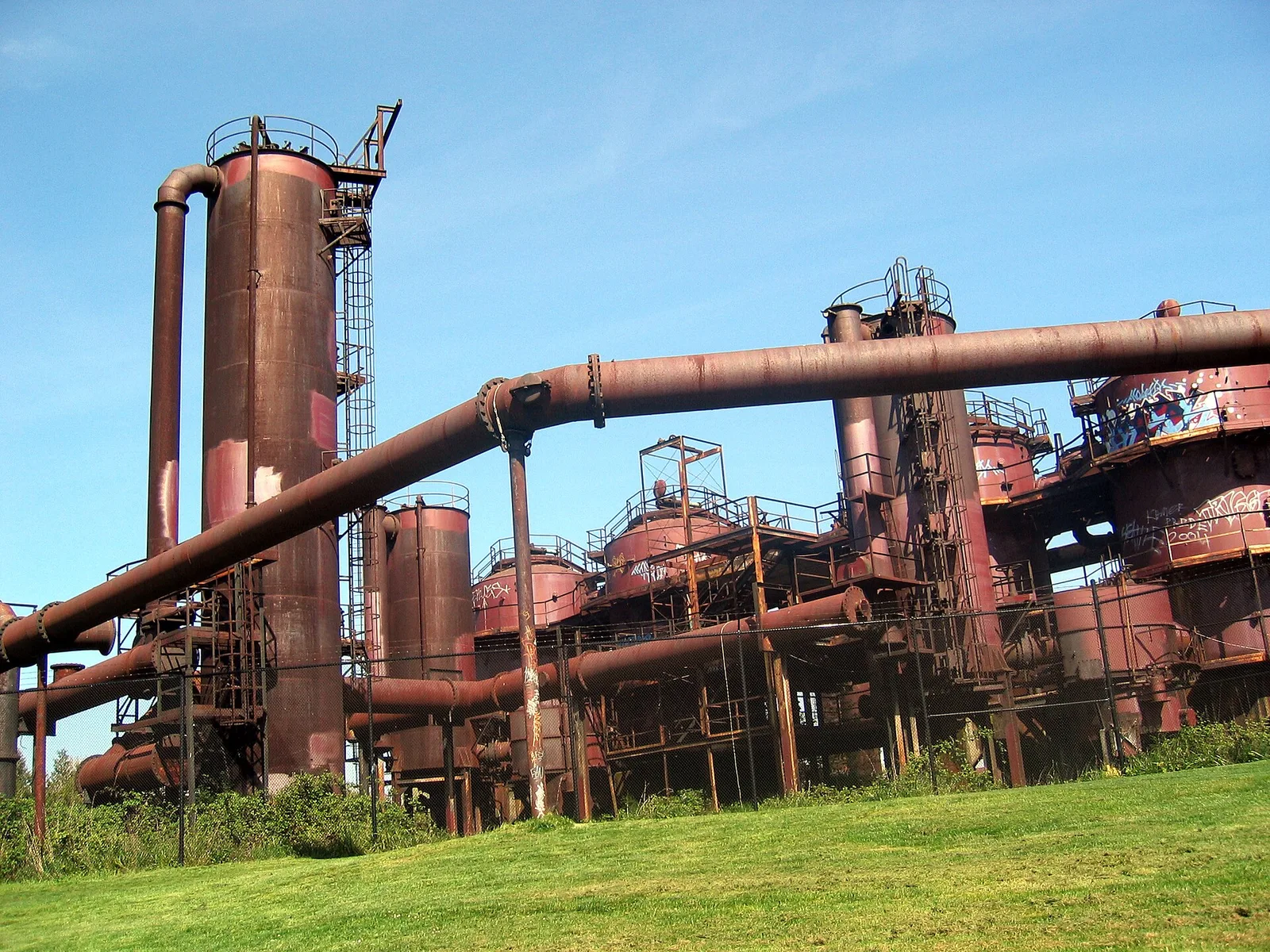 The rusted towers and pipes of the old gasification plant at Gas Works Park, with grass in the foreground