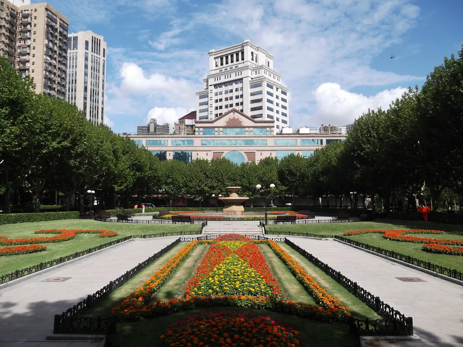 Flower beds and a fountain in formal Fuxing Park, with plane trees on both sides