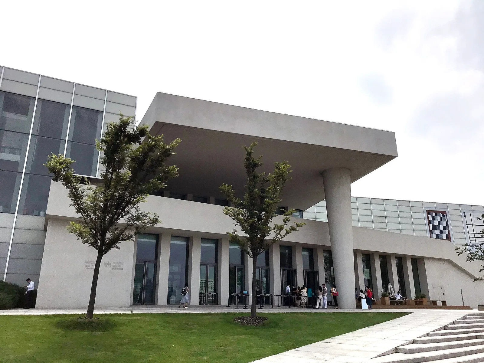 The concrete-and-glass entrance of the West Bund Museum with a large cantilevered roof