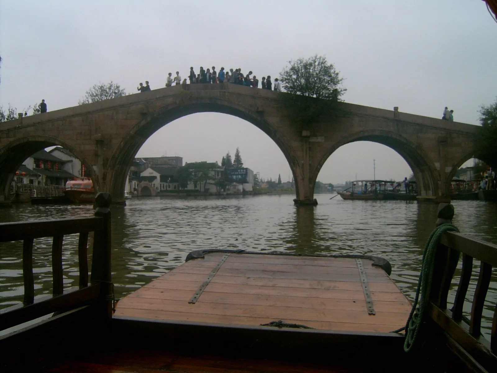 Fangsheng Bridge seen from a boat on the Zhujiajiao canal, with visitors on top of its stone arches