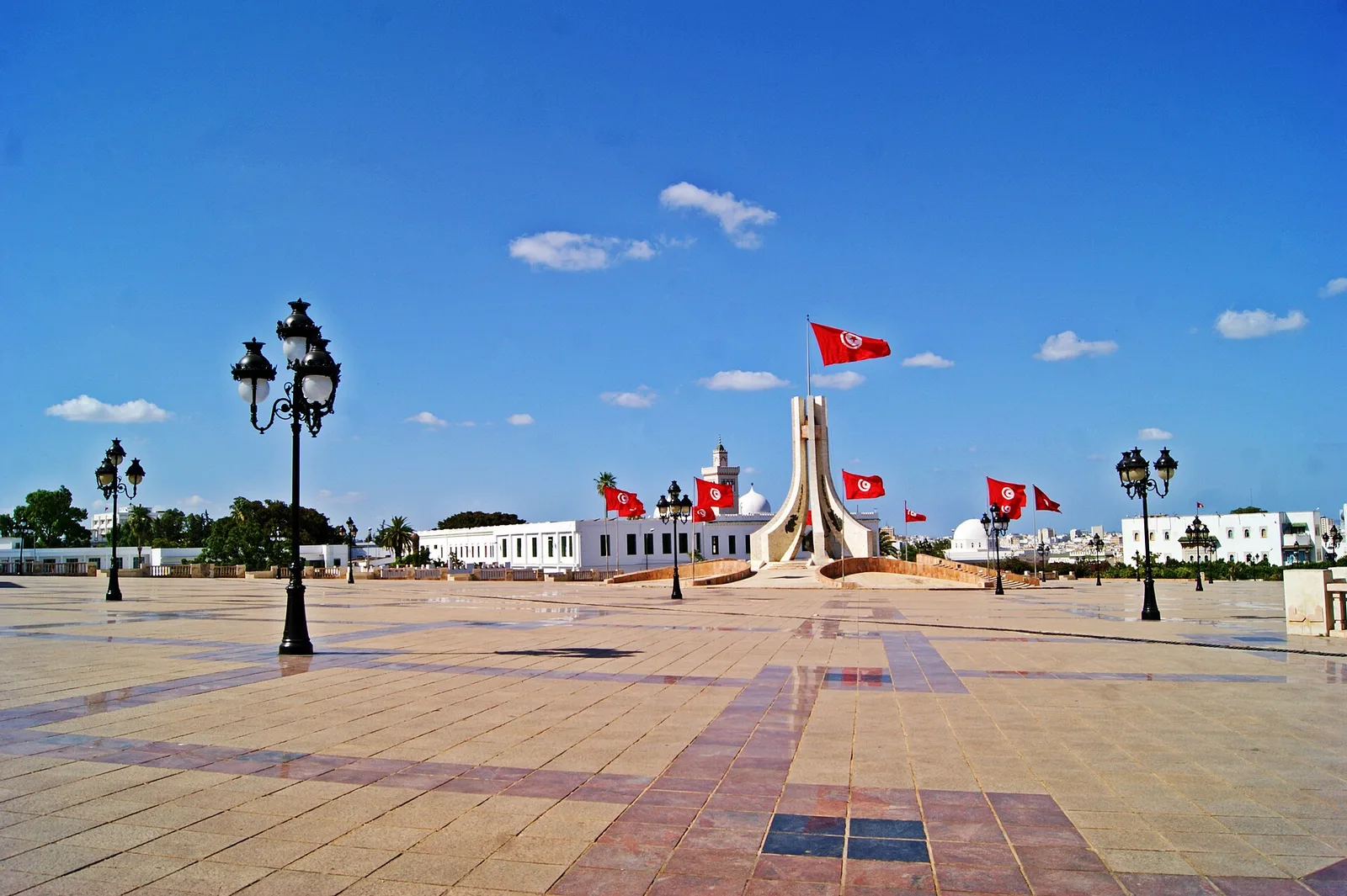 The wide paved Kasbah Square with lamp posts, Tunisian flags, and a monument at its centre