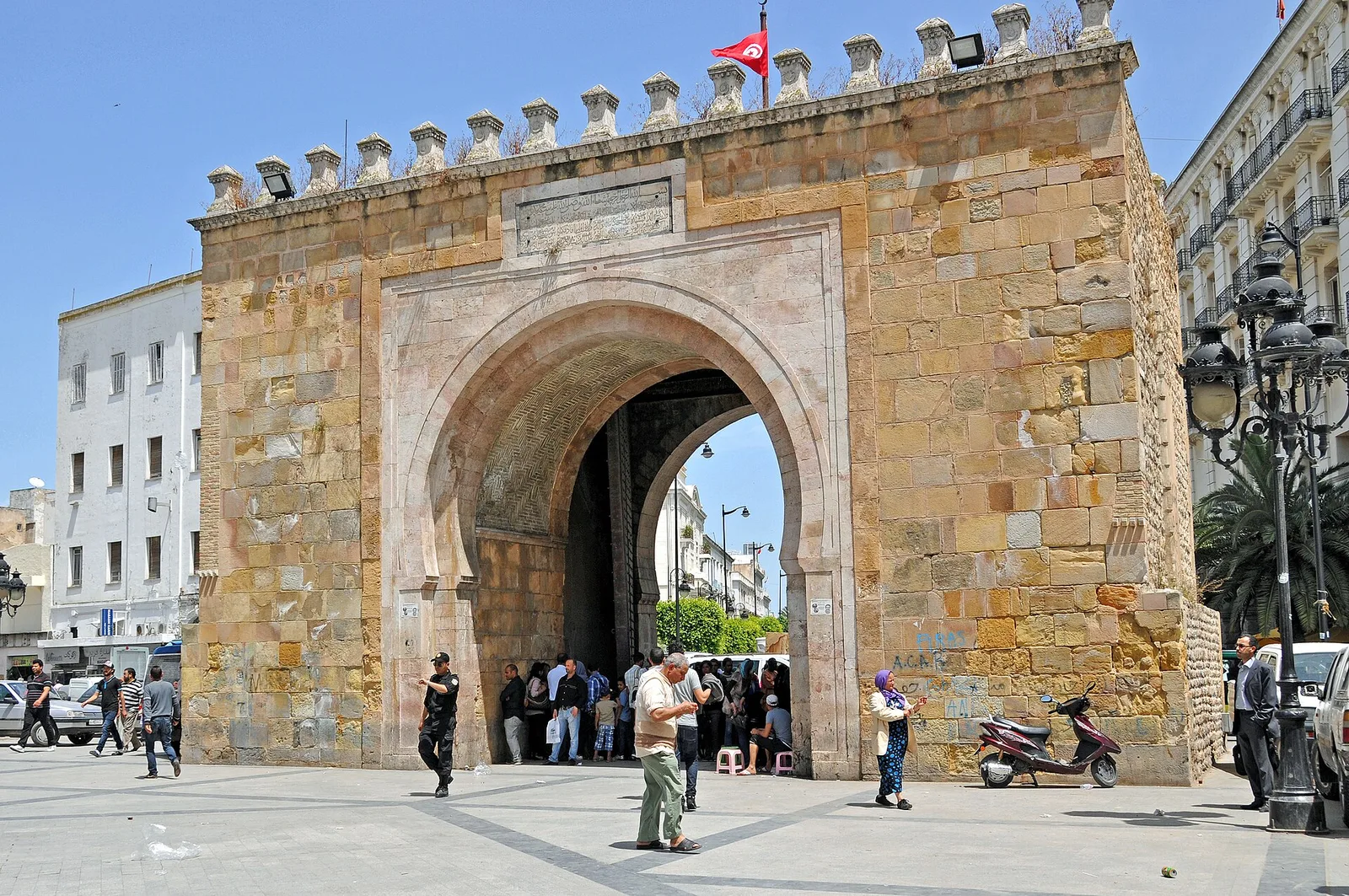 The sandstone Bab El Bhar gate with its horseshoe arch and crenellations, seen from the square in front