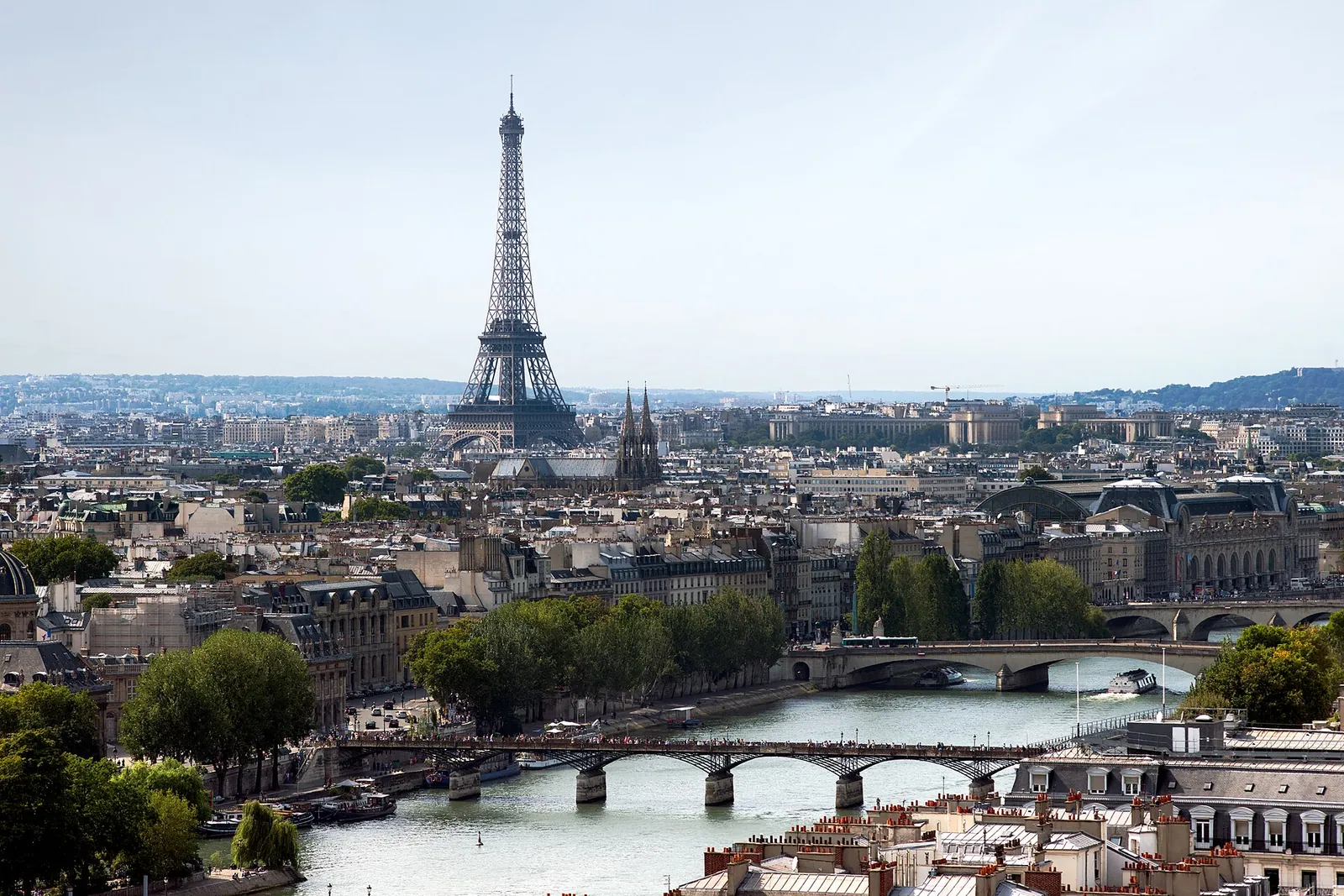 The Eiffel Tower rising above the rooftops of Paris, with the Seine and its bridges below